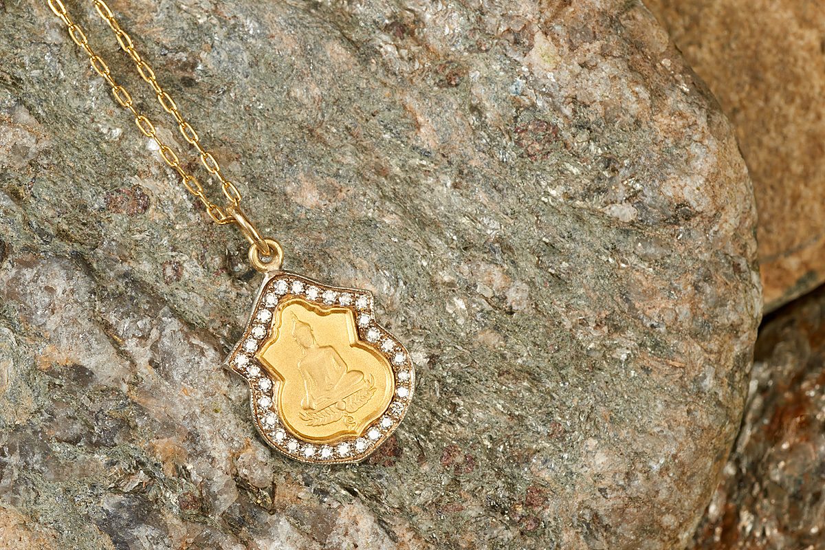 The Buddha medallion in 14k gold, resting on stone