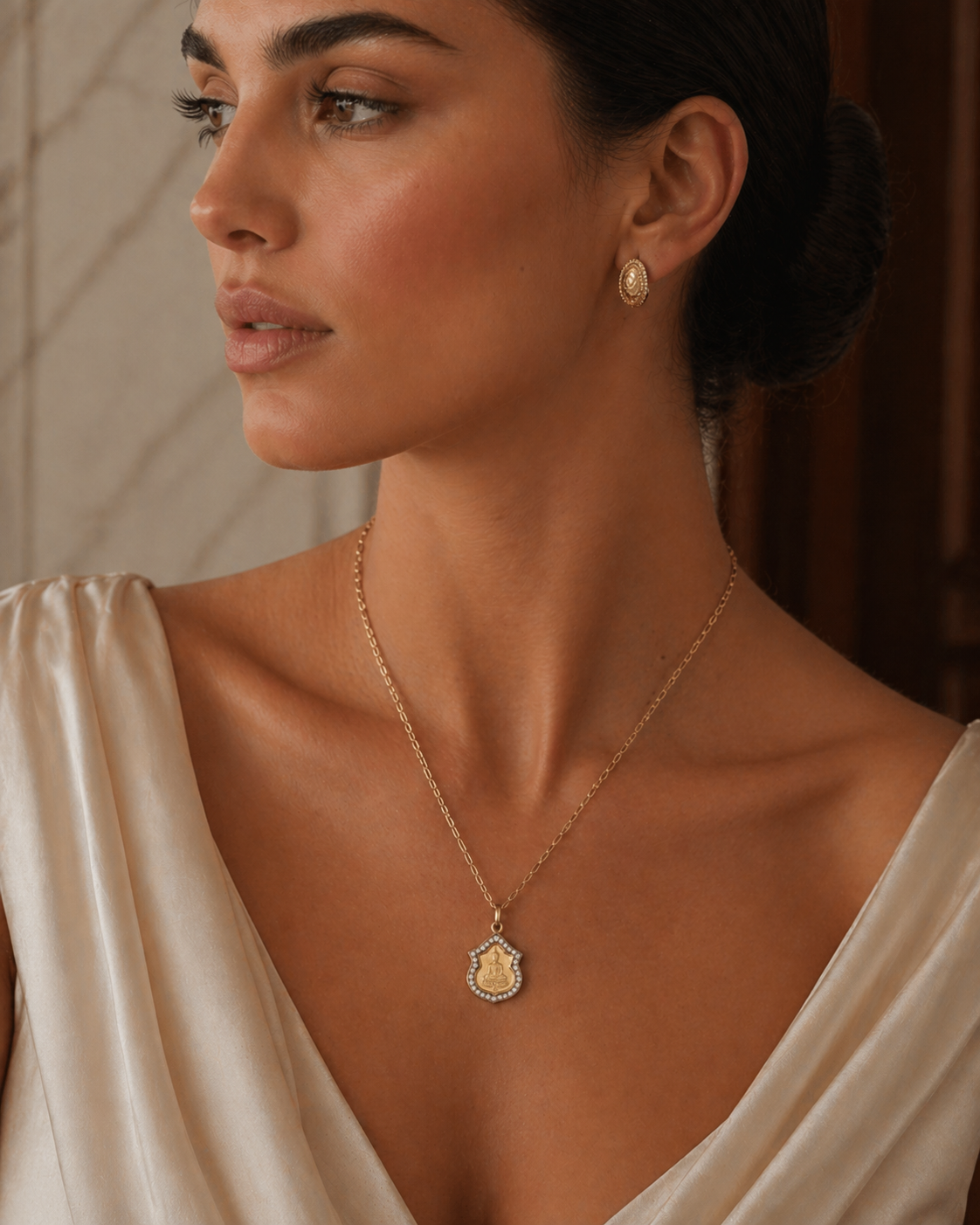 Model wearing the seated Buddha medallion in 14k gold with a diamond halo